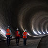 Drei Männer in Warnwesten gehen durch einen Tunnel des Bahnprojektes Stuttgart 21.