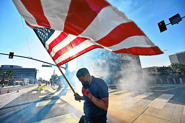Ein Demonstrant hält die US-Flagge, nachdem die Polizei Tränengas und Blendgranaten vor dem Bundesgebäude in Santa Ana, Kalifornien, ...