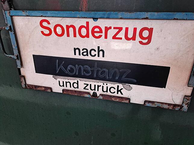 Ein Schild weist außen am Wagen auf das Ziel des Zugs hin.