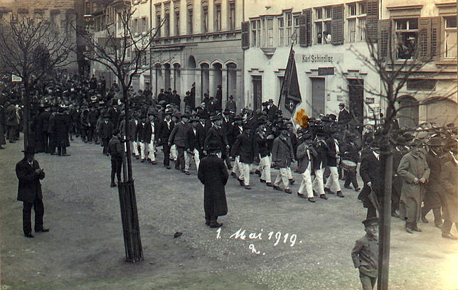 Konstanz, in der Kreuzlinger Straße, am 1. Mai 1919: Mit Fahnen und Musik marschieren Arbeiterverbände und Gewerkschaften.