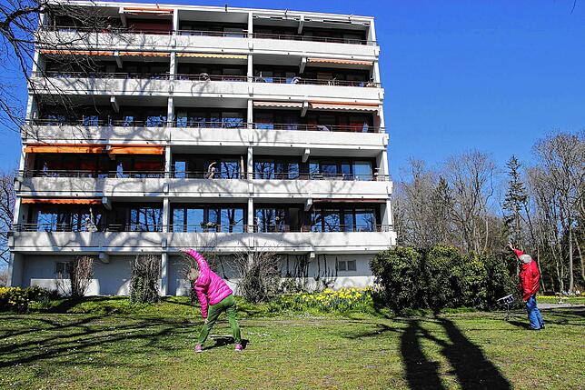 Vor dem Gebäude wird die Gymnastik vorgemacht, die Bewohner machen die Übungen auf ihren Balkonen nach.