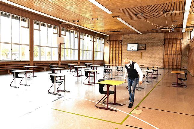 Konrektor Martin Schynala vergrößert in der Sporthalle der Bickebergschule die Tischabstände, wo ab Montag schrittweise der Unterricht ...