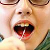 Ein Kind führt einen Lolli-Test durch (Symbolbild). Diese Tests werden vermehrt an Schulen eingesetzt.