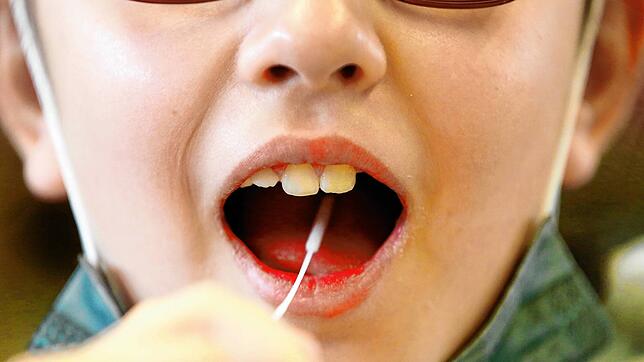 Ein Kind führt einen Lolli-Test durch (Symbolbild). Diese Tests werden vermehrt an Schulen eingesetzt.