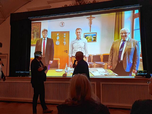 Landrat Martin Kistler und Moderator Wolfgang Endres stehen im St. Blasier Kursaal vor einer Leinwand mit einem Foto, das Kistler, ...