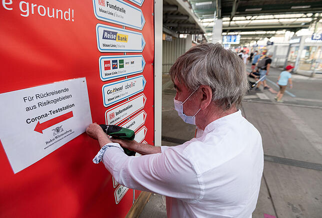 Covid-19-Teststation am Stuttgarter Hauptbahnhof 13.08.2020, Stuttgart: Ein Mitarbeiter des Sozialministeriums bringt im Hauptbahnhof Wegweiser zu einer Covid-19-Teststation für ...