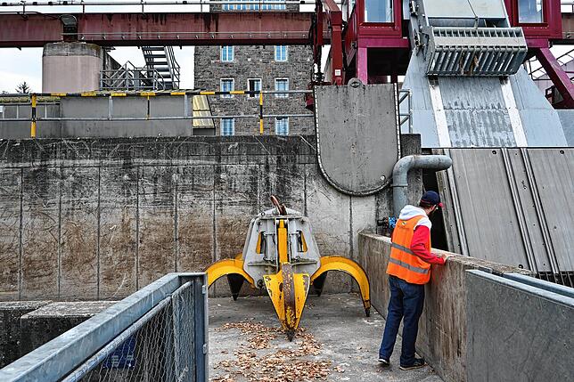 Mit dem gelben Greifer werden große Geschwemmselteile aus dem Wasser geholt.