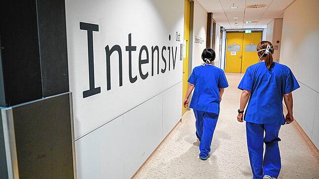 Symbolfoto: Zwei Pflegerinnen gehen im Bundeswehrkrankenhauses in Ulm im März letzten Jahres an dem Schriftzug &ldquo;Intensiv&bdquo; ...