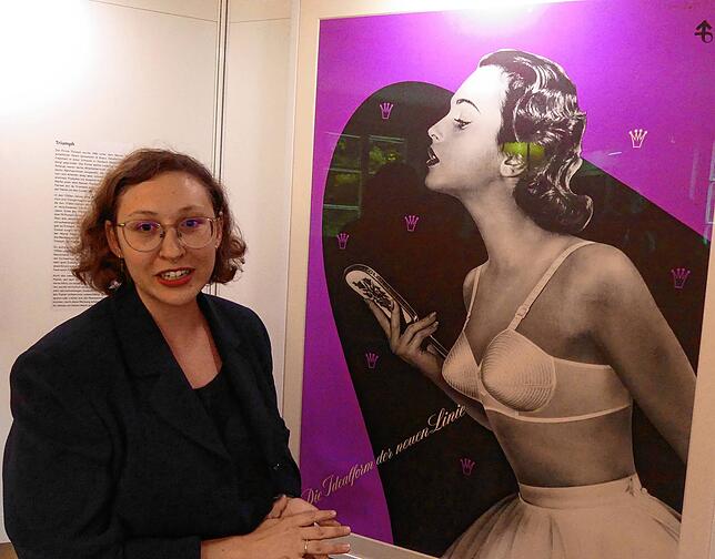 Die Ausstellungsinitiatorin Julia Berlitz vor einem Triumph-Werbeplakat, das vermutlich nie im Pfeifferschen Schaufenster hing.