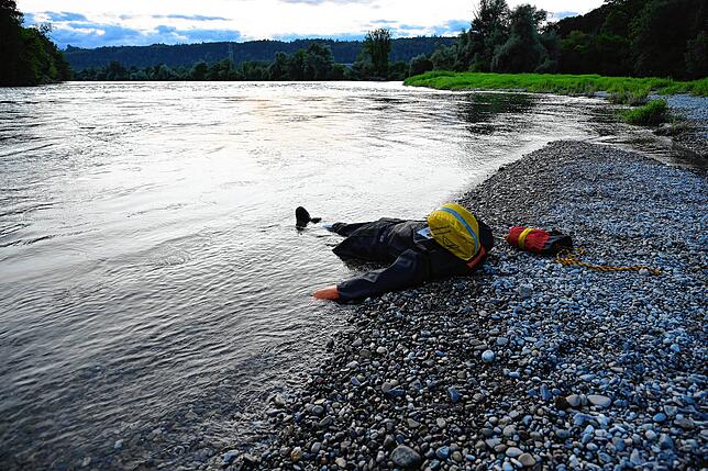Wasserrettungspuppe Justin liegt reglos am Rheinufer.