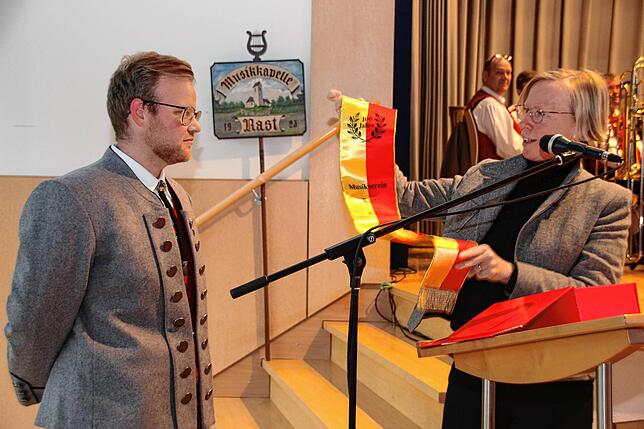Landrätin Stefanie Bürkle überreicht dem Musikvereinsvorsitzenden Philipp Bischof ein Fahnenband für die Vereinsfahne.