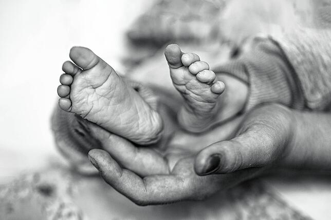 Eine Mutter hält die kleinen Füße ihrer verstorbenen Tochter. Es handelt sich um eines der Kinder, das Isabel Meyer fotografierte.