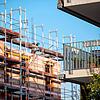 Ein Gerüst steht an der Baustelle eines Neubaus in Stuttgart. Neben der Baustelle steht ein bereits fertiggestellter Neubau. Wer in ...