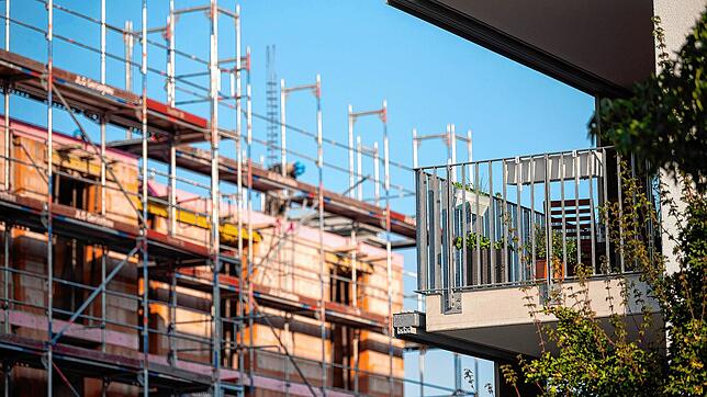 Ein Gerüst steht an der Baustelle eines Neubaus in Stuttgart. Neben der Baustelle steht ein bereits fertiggestellter Neubau. Wer in ...