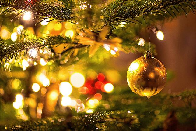 Eine goldene Kugel hängt an einem Weihnachtsbaum auf einem Weihnachtsmarkt.
