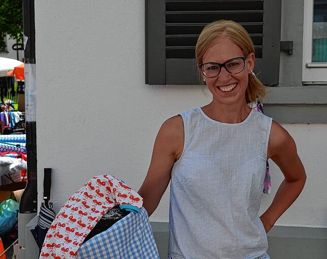 Yvonne Hartmann strahlt trotz der Hitze – ihre kleine Tochter hat ein schattiges Plätzchen gefunden für den Flohmarkt-Verkaufsstand.