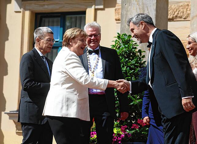 Angela Merkel (CDU), ehemalige Bundeskanzlerin, und ihr Mann Joachim Sauer (l) werden von Markus Söder (CSU, r), Ministerpräsident von ...