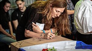 Ricarda Louk schreibt auf den bedeckten Sarg ihrer Tochter während ihrer Beerdigung. Die 22-jährige Shani Louk wurde auf der Flucht von ...