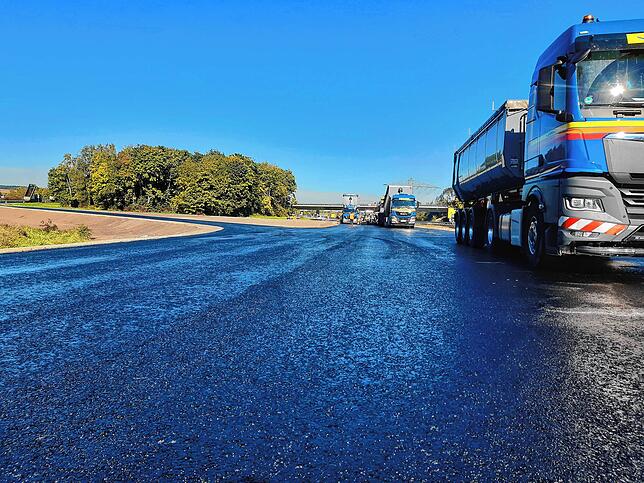 Glänzend neu präsentiert sich der frisch aufgesetzte Asphalt auf der Fahrbahn.