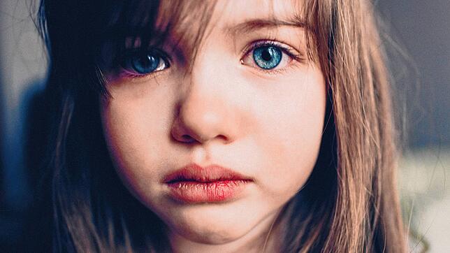 Tieftraurig: Ein Mädchen mit Tränen in den Augen. Wie kann man mit Kindern über einen Trauerfall reden?