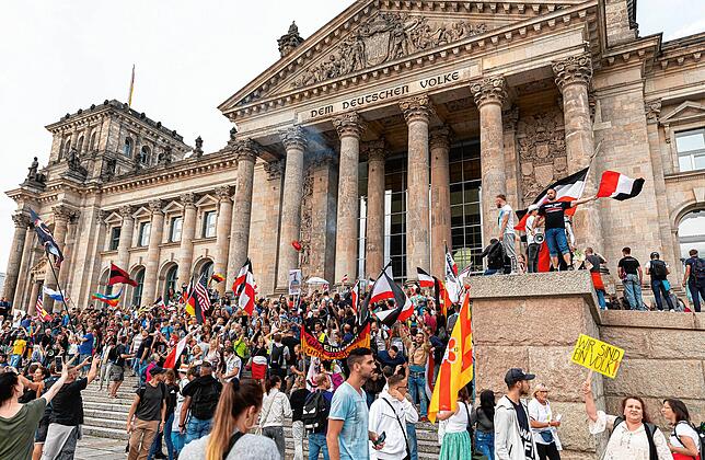 Teilnehmer der Kundgebung gegen die Corona-Maßnahmen stehen auf den Stufen zum Reichstagsgebäude, zahlreiche Reichsflaggen sind dabei zu ...