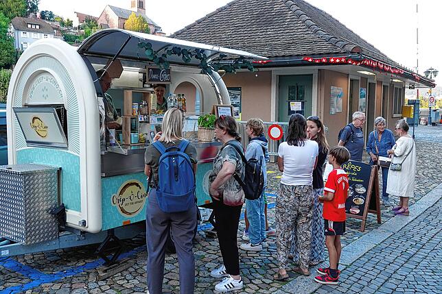 Menschen stehen bei der Kulturnacht 2024 vor einem Crepes-Stand, im Hintergrund das ehemalige Zollhaus im deutschen Laufenburg.