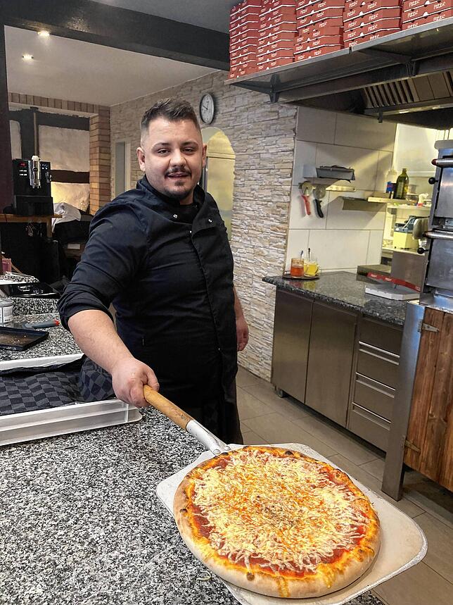 Atmin Fetai zeigt meine Pizza Margherita, die aus hausgemachtem Teig im Steinofen gebacken wird.