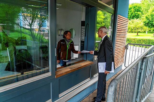 Schwimmmeistrin Véronique Kühn zeigt Bürgermeister Fritz Link, wie sie die Online-Reservierungen am Eingang einscannen und kassieren kann.