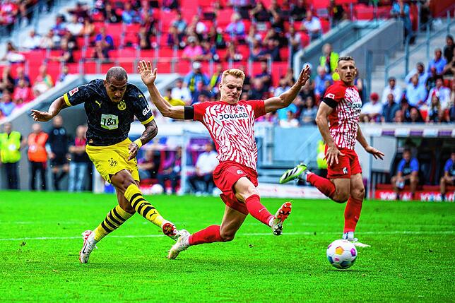 Dortmunds Donyell Malen (l) macht das Tor zum 2:2 gegen Freiburgs Philipp Lienhart (M) und Freiburgs Maximilian Eggestein (r).