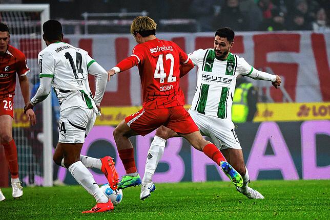 Freiburgs Ritsu Doan (m) springt zwischen Mönchengladbachs Alassane Plea (l) und Mönchengladbachs Tim Kleindienst (r) hindurch.