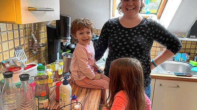 Tagesmama Nadine Klopcke stellt mit Tageskind Cecilia und Besucherkind Aliya Glitzerflaschen in der Küche her.