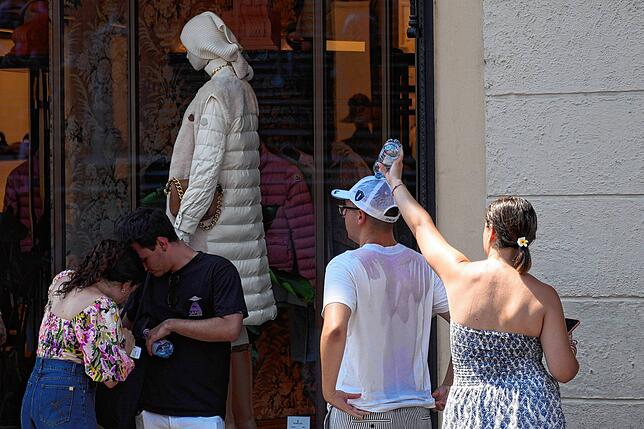 Kalte Dusche: Touristen kühlen sich in Rom im Schatten eines Schaufensters ab.