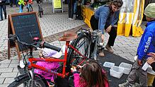 Kunsstoffbecher werden durch das fleißige Treten auf einem Fahrrad zerkleinert, um danach in der Presse zu neuen Gegenständen ...