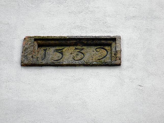 Bei Baumaßnahmen im 16. Jahrhundert wurde diese Steintafel an der Westfassade eingelassen.