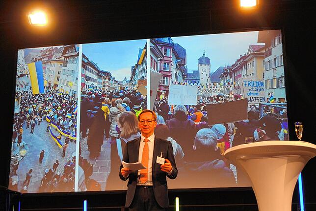 Oberbürgermeister Philipp Frank steht vor einer Bildercollage, die Fotos von der Solidaritätskundgebung für die Ukraine im März 2022 in ...