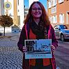 Elena Williams vom Stockacher Stadtarchiv präsentiert den historischen Kalender 2025 vor der St. Oswald-Kirche.