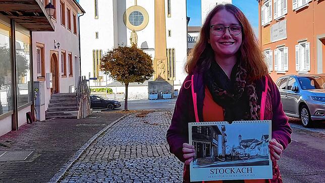 Elena Williams vom Stockacher Stadtarchiv präsentiert den historischen Kalender 2025 vor der St. Oswald-Kirche.