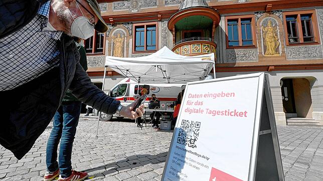 Ein Mann scannt in Tübingen mit seinem Handy in der Innenstadt vor einer Corona Schnelltest-Station einen QR-Code für einen ...