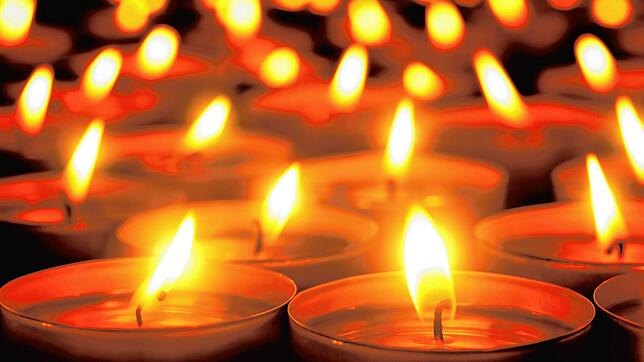 Many candle flames glowing in the dark, create a spiritual atmosphere
