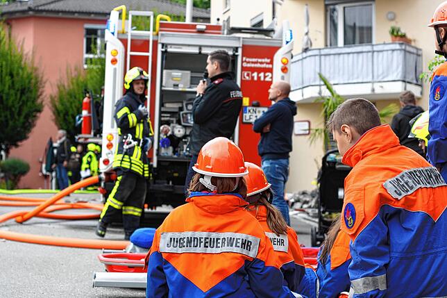 Jugendwart Tobias Rosen kommentiert den Ablauf, während im Vordergrund die Mitglieder der Jugendfeuerwehr arbeiten.