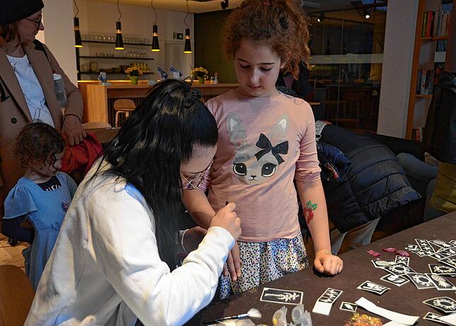 Soraya (9) lässt sich von Jasmine Schütz Glitzer-Tatoos auf die Arme kleben.