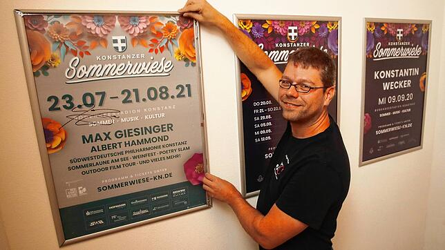 Jürgen Nägele, Mitveranstalter der Konstanzer Sommerwiese, hängt das diesjährige Plakat mit Autogramm von Max Griesinger ins Treppenhaus ...