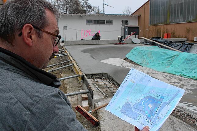 Detlef Kohler vom Stadtbauamt Markdorf vor dem entstehenden Flowpark. Er betrachtet den Plan der künftigen Trendsportanlage.