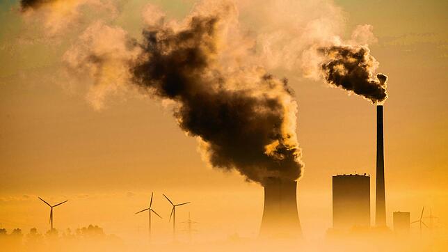 Windräder drehen sich neben einem Kohlekraftwerk. Die Umsetzung der Energiewende ist für viele Industriezweige fundamental wichtig, um ...