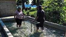 Zwei Urlauber laufen im Storchengang durch das Kneippbecken in den Villengärten. Zwischen Wassertreten und Armbad sollten ein bis zwei ...