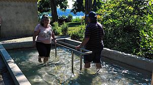 Zwei Urlauber laufen im Storchengang durch das Kneippbecken in den Villengärten. Zwischen Wassertreten und Armbad sollten ein bis zwei ...
