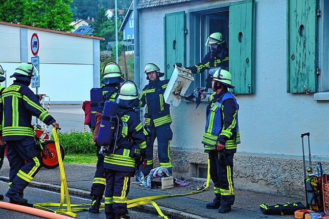 Die Feuerwehr bringt den verbrannten und verschmorten Hausrat ins Freie.