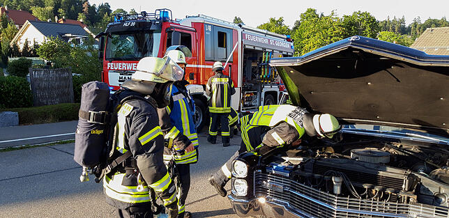 Die Feuerwehr inspiziert den Motorraum des Fahrzeugs, dessen Fahrer Rauchentwicklung festgestellt hat.