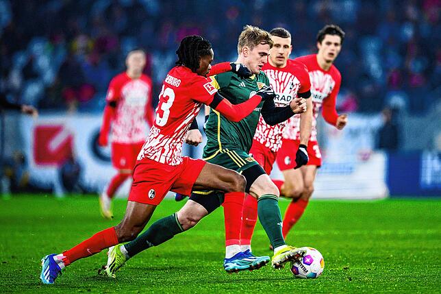 Union Berlins Mikkel Kaufmann (M) in Aktion gegen Freiburgs Jordy Makengo (l) und Freiburgs Maximilian Eggestein (r)