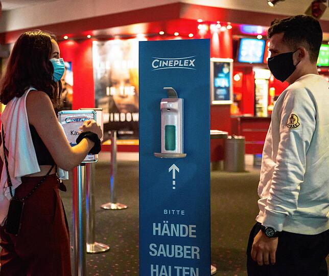 Lisa Henzler und Maximilian Brauchle desinfizieren sich die Hände am Eingang des Cineplex.